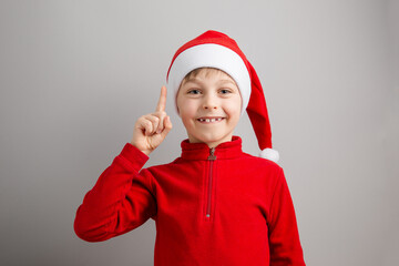 Cheerful boy in Santa hat on isolated gray background showing different funny emotions, surprise, joy, delight.