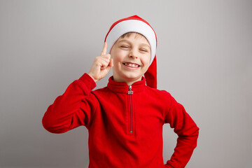 Cheerful boy in Santa hat on isolated gray background showing different funny emotions, surprise, joy, delight.