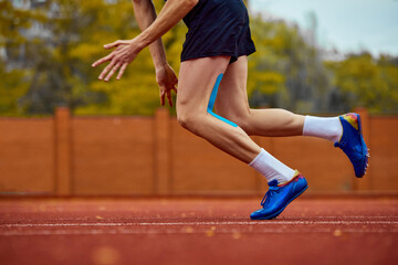 Dynamic strides hinting at upcoming leap. Cropped photo of male sportsman fast running on sport...