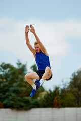 Acrobat's precision displayed in mid-air phase of long jump. Athletic man, professional sportsman...