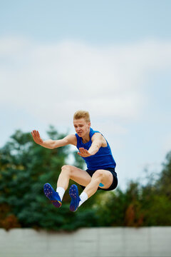 photo capturing climax of long jump, frozen in motion. Athletic man, professional sportsman sets new long jump record.