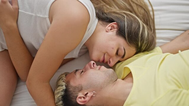 Beautiful couple smiling confident lying on bed kissing at bedroom