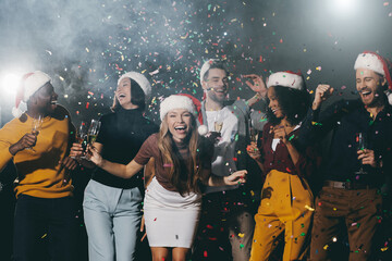 Happy young people enjoying champagne and dancing while celebrating New Year in night club together