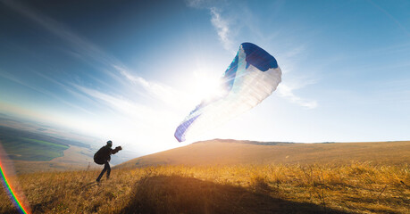 paraglider with a blue parachute takes off. A man takes off and lands on a yellow field. a man...