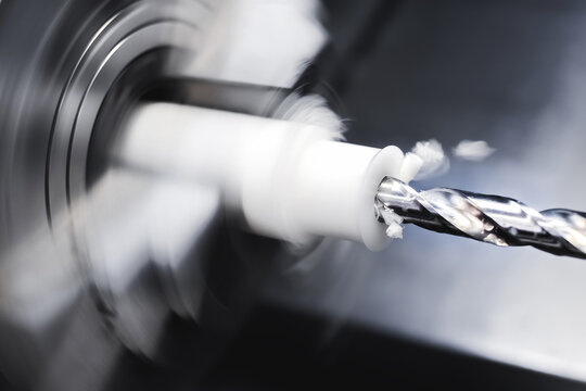 Operation of a CNC lathe on a workpiece made of textolite or polyethylene or propylene. Automation of the production base. The chips are flying.