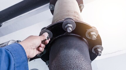 Technician check and inpection the bolt mounting exhaust muffler with flexible metal bellows on the...