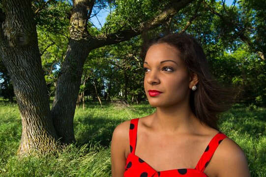 Close-up outdoor portrait on a beautiful young woman in a red polka dot dress; Bennet, Nebraska, United States of America