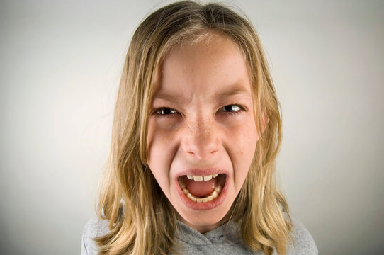 Preteen girl with an angry expression against a grey background; Studio