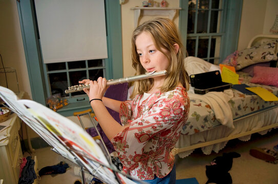 Girl practices the flute in her bedroom; Lincoln, Nebraska, United States of America