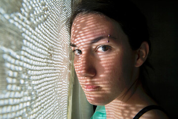 Young woman poses next to a lace curtain; Bennet, Nebraska, United States of America