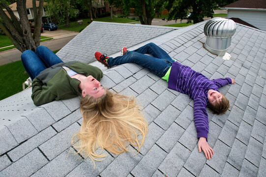 Boy and teenage girl lay on rooftop of house; Elkhorn, Nebraska, United States of America