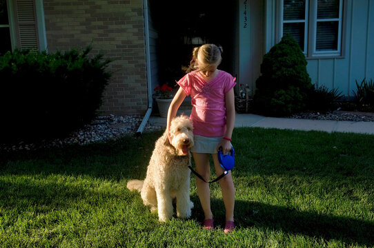 Young girl plays with her pet fanci doodle in her yard; Elkhorn, Nebraska, Unied States of America