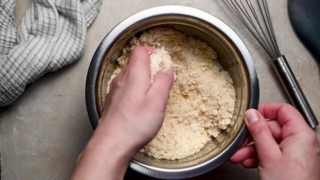 Kneading shortbread raw dough in bowl with hands. Baking at home concept.