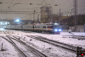 Arrival of a passenger electric train at the railway station on a winter night. Railway passenger...