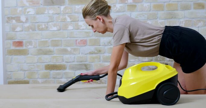 Woman cleaning sofa at home by steam cleaner