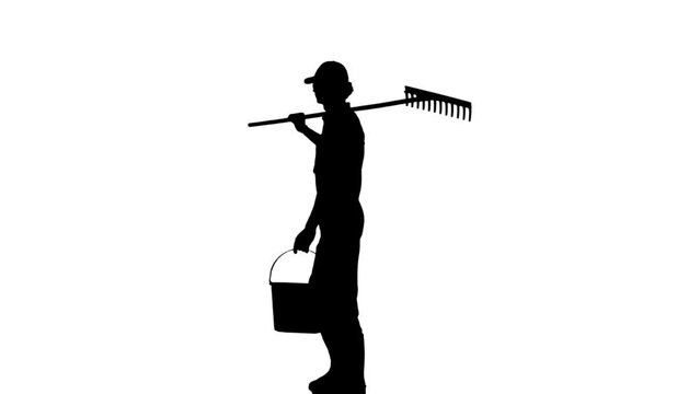 Silhouette of man gardener in hat walking with rake and bucket through the farm. Isolated on white background alpha channel.