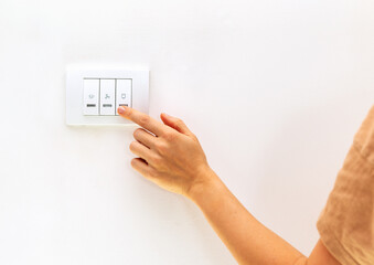 Reduction in electricity consumption. Female finger on light switch close up.