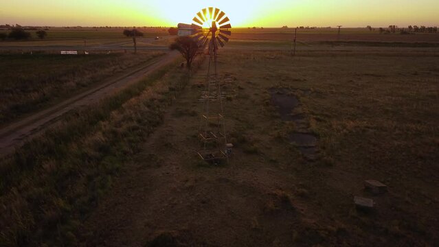 Molino de viento en contraluz en el ocaso en la extensa llanura 