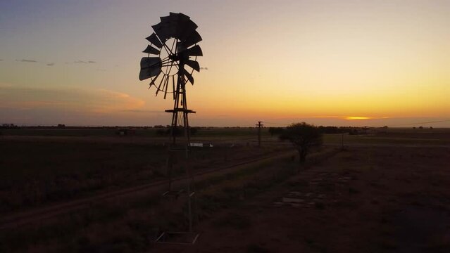 Molino de viento al atardecer en cotraluz  en la extensi&oacute;n de la llanura captado por un dron sobrevolando lentamente