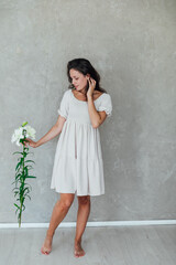 Fototapeta premium Beautiful brunette woman in white summer dress with beautiful flower