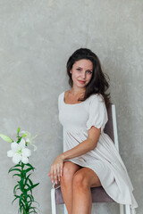 Obraz na płótnie Canvas Beautiful brunette woman in white summer dress with beautiful flower