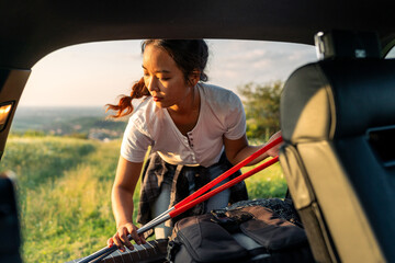 young adventurer adjusts her equipment before - after hiking in her car