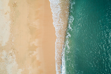 Fototapeta na wymiar Aerial view of sandy beach and turquoise ocean. Top view of ocean waves reaching shore on sunny day.