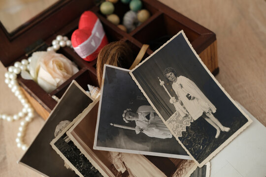 close-up dear to heart memorabilia in an old wooden box, lock of hair, stack of retro photos, vintage photographs 40s - 50s, concept family tree, genealogy, memories, home archive, keep as keepsake