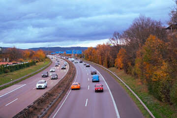 Passenger and freight vehicles travel along A5 autobahn in Germany, with Taunus mountains in...