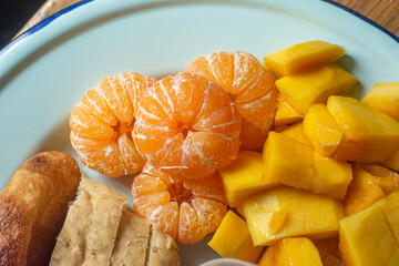 fresh fruit, orange, mango and bread served on a plate for breakfast
