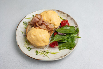Delicious breakfast - Eggs Benedict with bacon and tomatoes