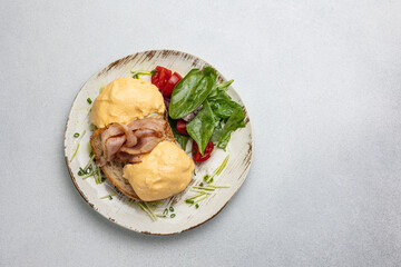 Delicious breakfast - Eggs Benedict with bacon and tomatoes