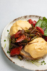 Delicious breakfast - Eggs Benedict with fried vegetables and tomatoes