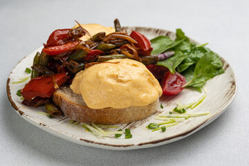 Delicious breakfast - Eggs Benedict with fried vegetables and tomatoes