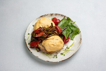 Delicious breakfast - Eggs Benedict with fried vegetables and tomatoes