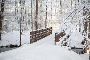 Wooden bridge over a river in the snow in winter.