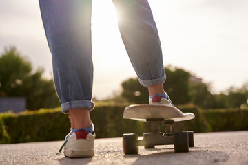 close-up of the legs of an unrecognizable woman riding a skateboard in bright sunshine
