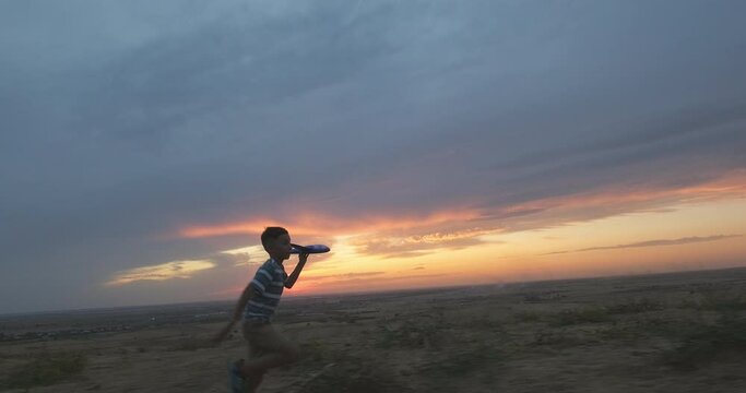 Silhouette of happy boy running with toy plane against stunning sunset backdrop. Happy kid at sunset