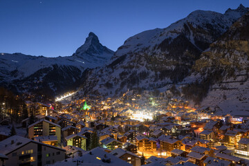 Panoramic landscape of Zermatt city Valley famous travel ski resort and iconic Matterhorn peak at dawn in the swiss alps, Switzerland. The snow covered village and church in Canton Valais in winter. - obrazy, fototapety, plakaty