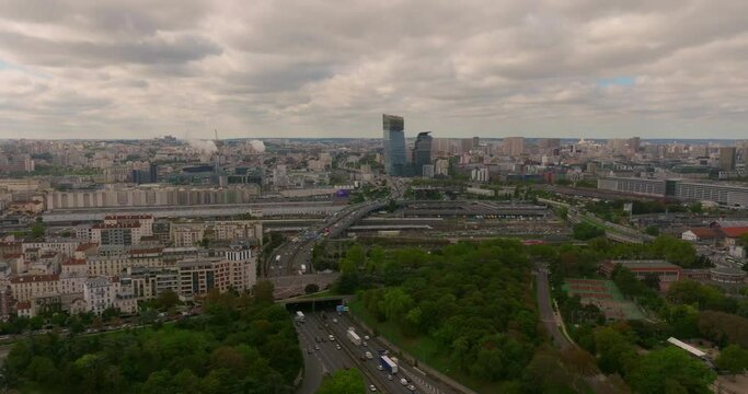 Establishing shot of the streets of Paris in the summer. Drone shot of french streets are full of cars and people. Aerial view, above trees and traffic, surrounded by french buildings and architecture