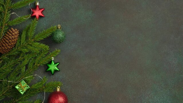 Stop motion looping 4k video with twinkling garland on the branches of Christmas tree on dark green background. Christmas decoration. Holiday background, copy space. 