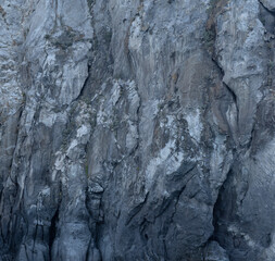 Weathered seaside rock face texture. Aged volcanic stone wall surface background pattern with cracks and scratches. Ischia Island, Italy.