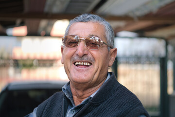 Close up of handsome old man with eyeglasses looking at camera and laughing.