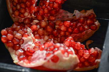 Organic pomegranate fruit with its seeds on a dark grey wooden background as a organic food concept