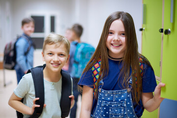 Portrait of smiling schoolboy and schoolgirl at lockers in school