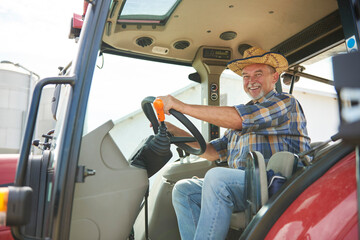 Portrait of smiling senior farmer on tractor