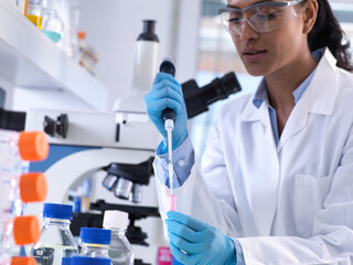 Genetic research, female scientist pipetting DNA or chemical sample into a eppendorf vial, analysis...