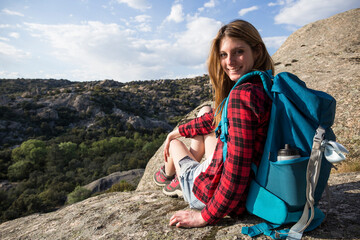 Spain, Madrid, smiling young woman resting on a rock during a trekking day