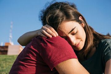 Couple embracing while sitting against clear sky