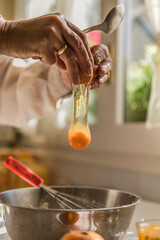 Hands of woman cracking egg into bowl